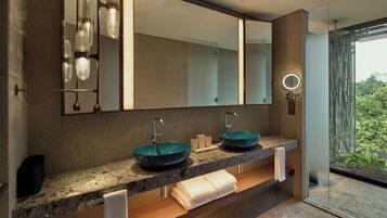 Un baño moderno con dos lavamanos, un espejo grande y vistas a zonas verdes.