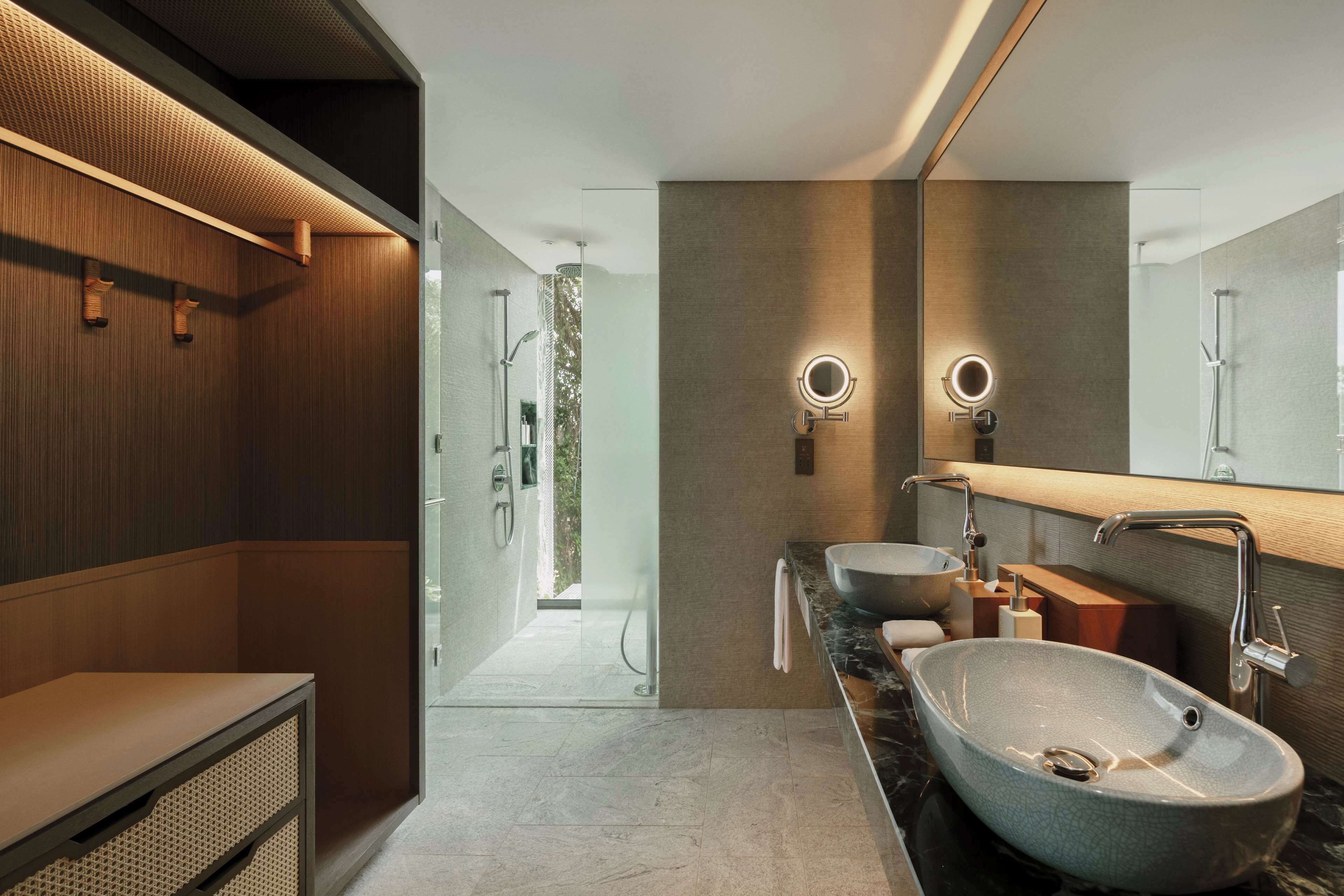 Une salle de bain moderne avec un grand miroir, deux lavabos et un espace douche.