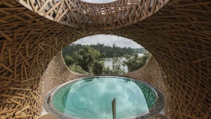 Una estructura circular de madera con una piscina en el centro, rodeada por un celosí­a de madera.