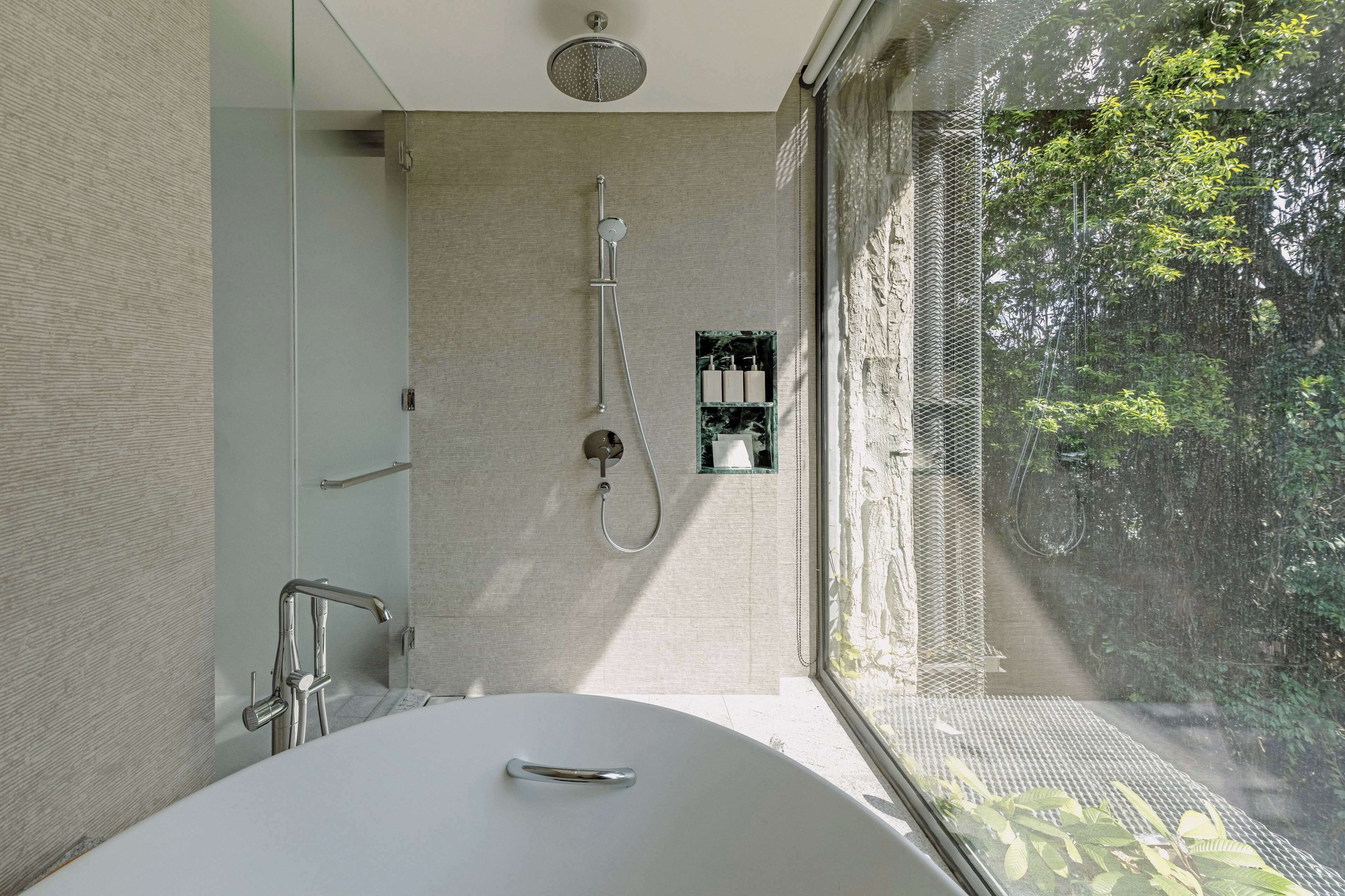 Un baño moderno con una bañera independiente, un cabezal de ducha y una zona de ducha con mampara de vidrio.
