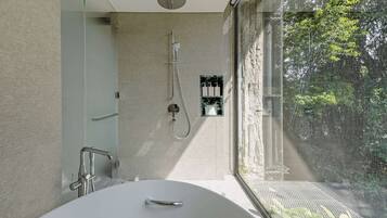 Un baño moderno con una bañera independiente, un cabezal de ducha y una zona de ducha con mampara de vidrio.