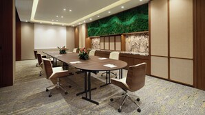 Un salón de conferencias con una larga mesa, seis sillas, un decorativo revestimiento de pared y suelo alfombrado.
