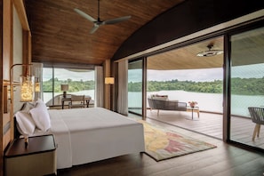 A bedroom with a bed, a desk, and a chair, a balcony with a view of a lake, and a ceiling fan. - Mandai Rainforest Resort By Banyan Tree (Singapore)