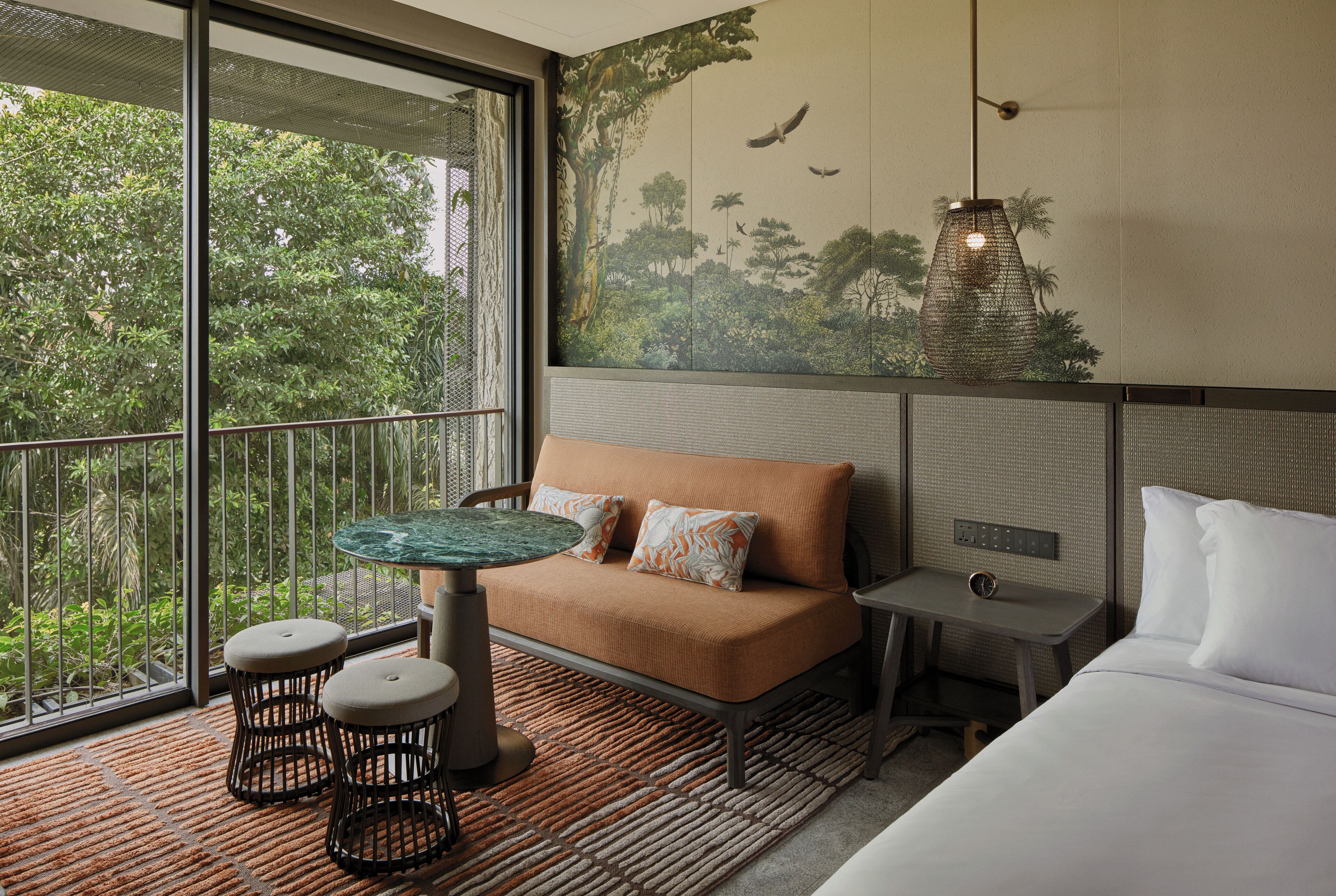 A room with a large window, a sofa, a small table, and a bed.