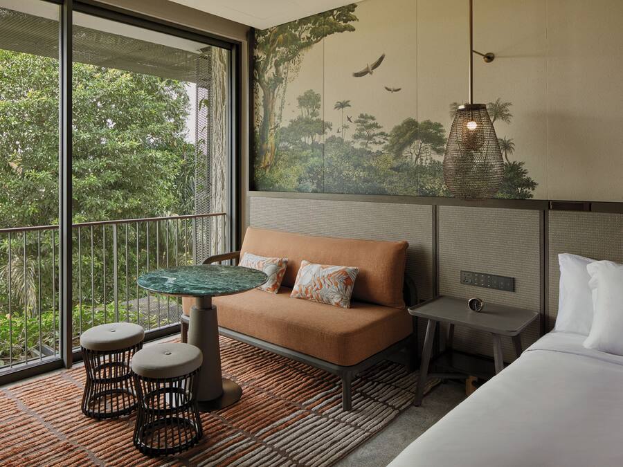 A room with a large window, a sofa, a small table, and a bed.