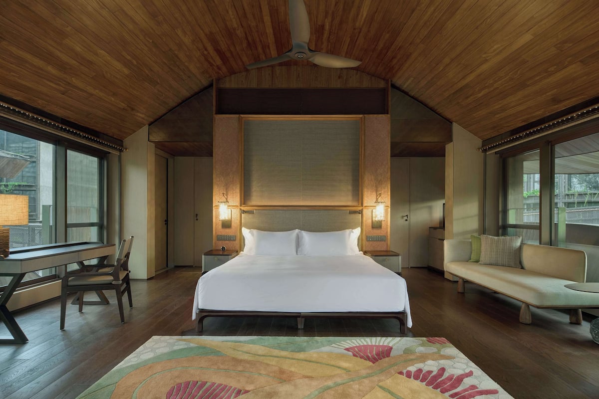 Un'ampia camera da letto con un letto grande, soffitto in legno e vista dalla finestra.