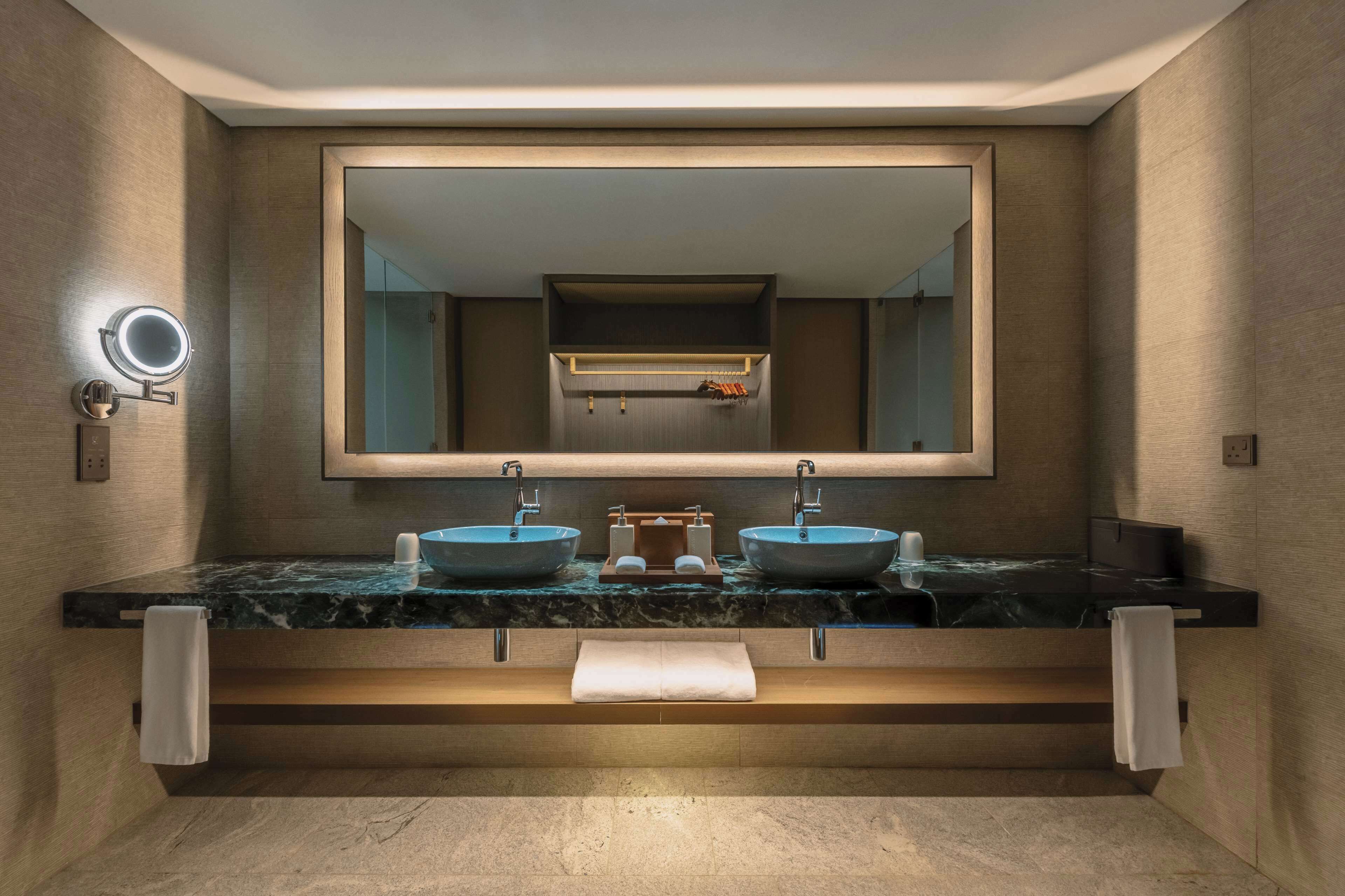 A modern bathroom with two vessel sinks, a large mirror, and a towel rack.