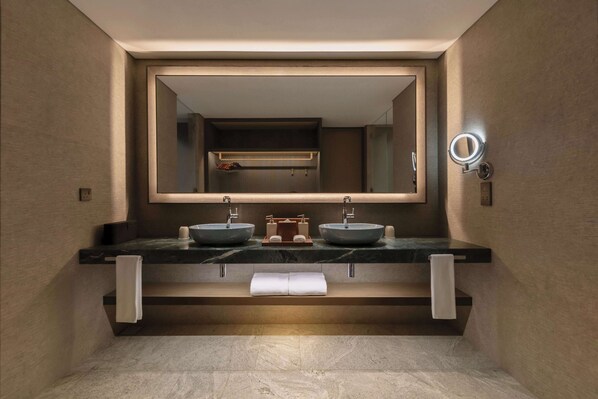 A modern bathroom with a large mirror, two sinks, and a towel rack.