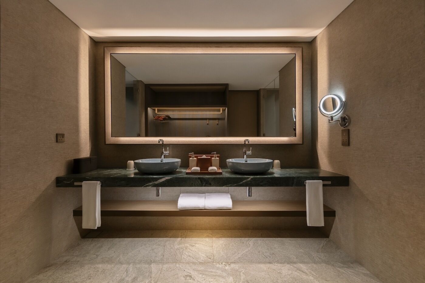 Un baño moderno con dos lavabos, un espejo grande y una luz de aro.