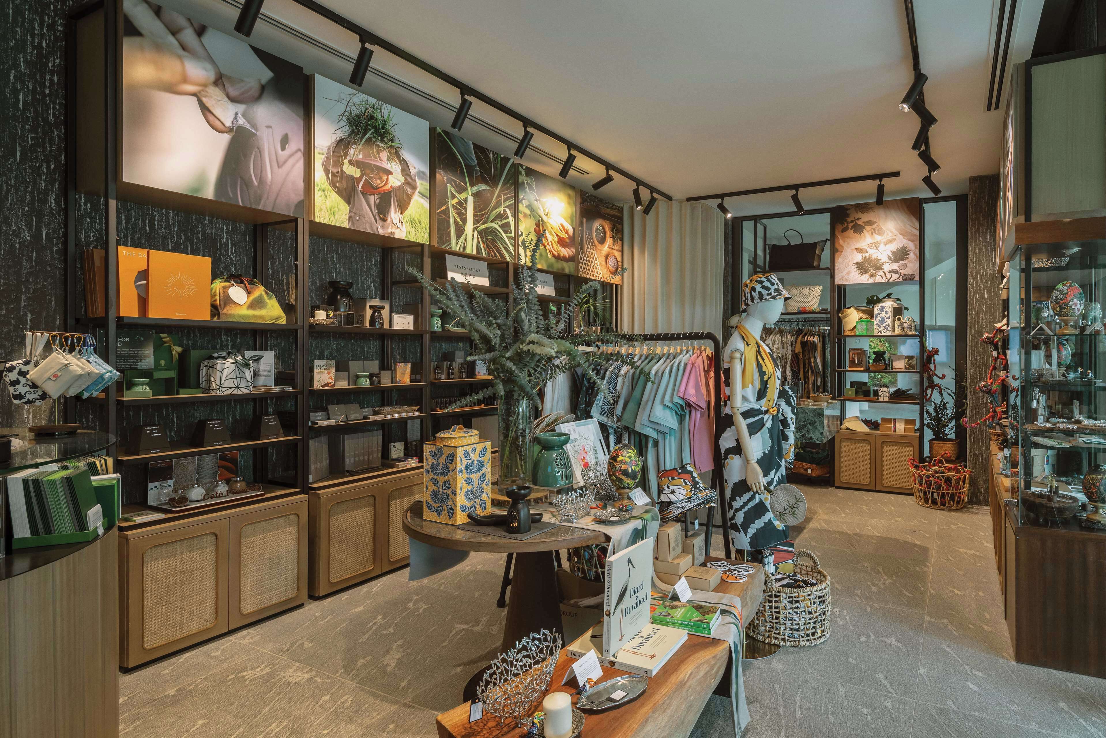 Uma loja boutique com estantes de livros, objetos decorativos e um manequim vestido com roupas coloridas.