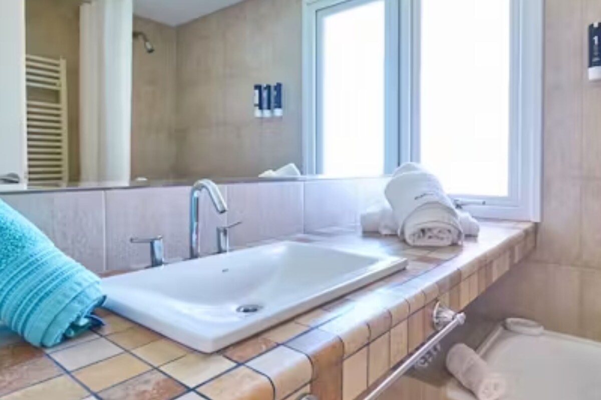 A bathroom with a white sink, a towel rack, and a window.
