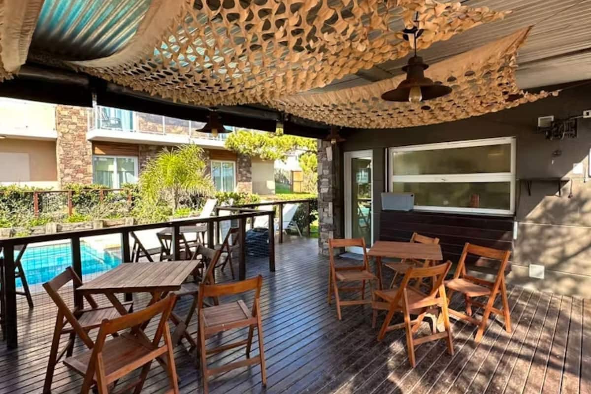 Eine Terrasse im Freien mit Holzmöbeln und einem Pool.