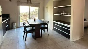 Une cuisine moderne avec une table à manger, des chaises et une étagère intégrée.