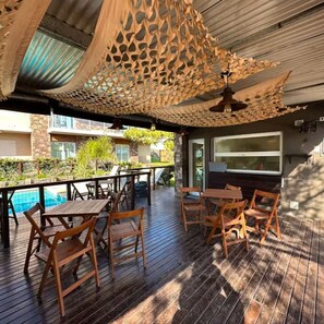 An outdoor patio with wooden furniture and a pool. - Punto Playa (Villa Gesell)