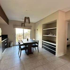 A modern kitchen with a dining table, chairs, and a built-in shelf unit. - Punto Playa (Villa Gesell)