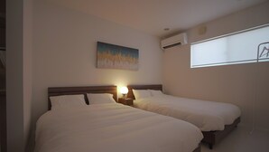 A hotel room with two beds, a nightstand with a lamp, an air conditioning unit, and a window with a view. - INOVE VILLA RITTO (Ritto)