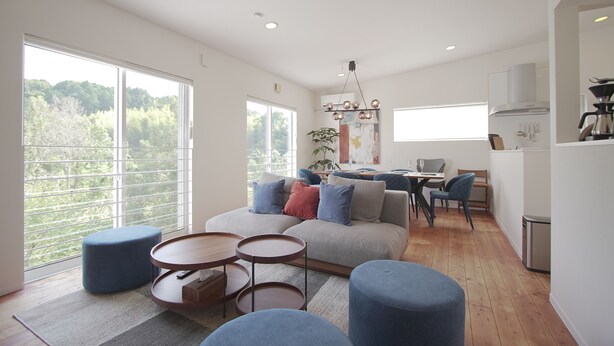 A modern living room with a sofa, ottomans, and a dining area with a table and chairs. - INOVE VILLA RITTO (Ritto)