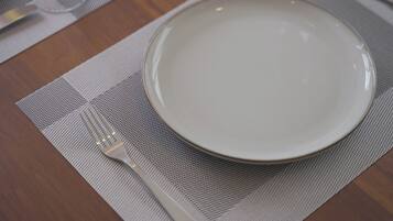 A table set with a white plate, a fork, and a wine glass on a textured placemat.