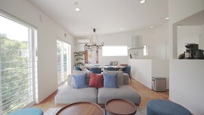 A modern living room with a grey sectional sofa, wooden coffee table, and a dining area with a table and chairs. - INOVE VILLA RITTO (Ritto)