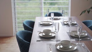 A dining table set with plates, bowls, cutlery, and glasses, with a view of greenery through the window. - INOVE VILLA RITTO (Ritto)