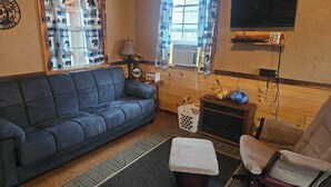 A cozy living room with a blue sofa, a wooden coffee table, a beige armchair, and a patterned rug.