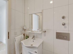 A modern bathroom with a white sink, a mirror, and a towel hanging on the wall. - Oberhausen Urban Retreat (Oberhausen)