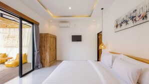 Une chambre d’hôtel moderne dotée d’un grand lit, d’une armoire en bois, d’une télévision et d’une porte-fenêtre coulissante donnant sur un balcon avec des chaises jaunes.