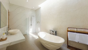Une salle de bain moderne dotée d’une grande baignoire, d’une douche à parois de verre et d’un meuble-lavabo en marbre.