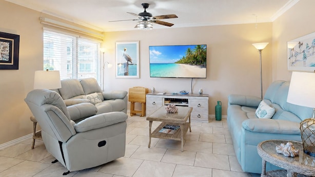 Ein Wohnzimmer mit Sofa, Couchtisch, Fernseher und Deckenventilator.