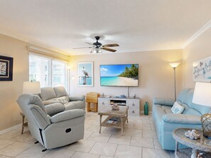 A living room with a sofa, a coffee table, a TV, and a ceiling fan.