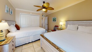 A hotel room with two beds, a ceiling fan, a nightstand with a lamp, a wooden dresser, and a door leading to a closet. - Beach Access Across the Street, Shared Heated Pool, Pet Friendly (Corpus Christi)