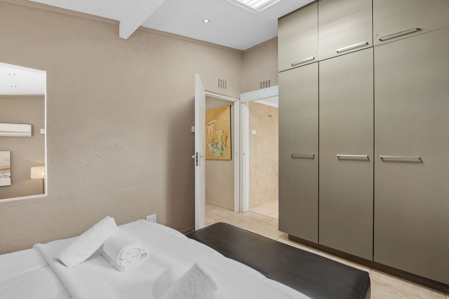 A modern hotel room with a bed, a wardrobe, and a painting on the wall.