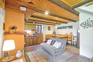 A cozy kitchen with wooden beams, a grey sofa, and a dining area. - Rustico Ca del Pol (Cugnasco-Gerra)