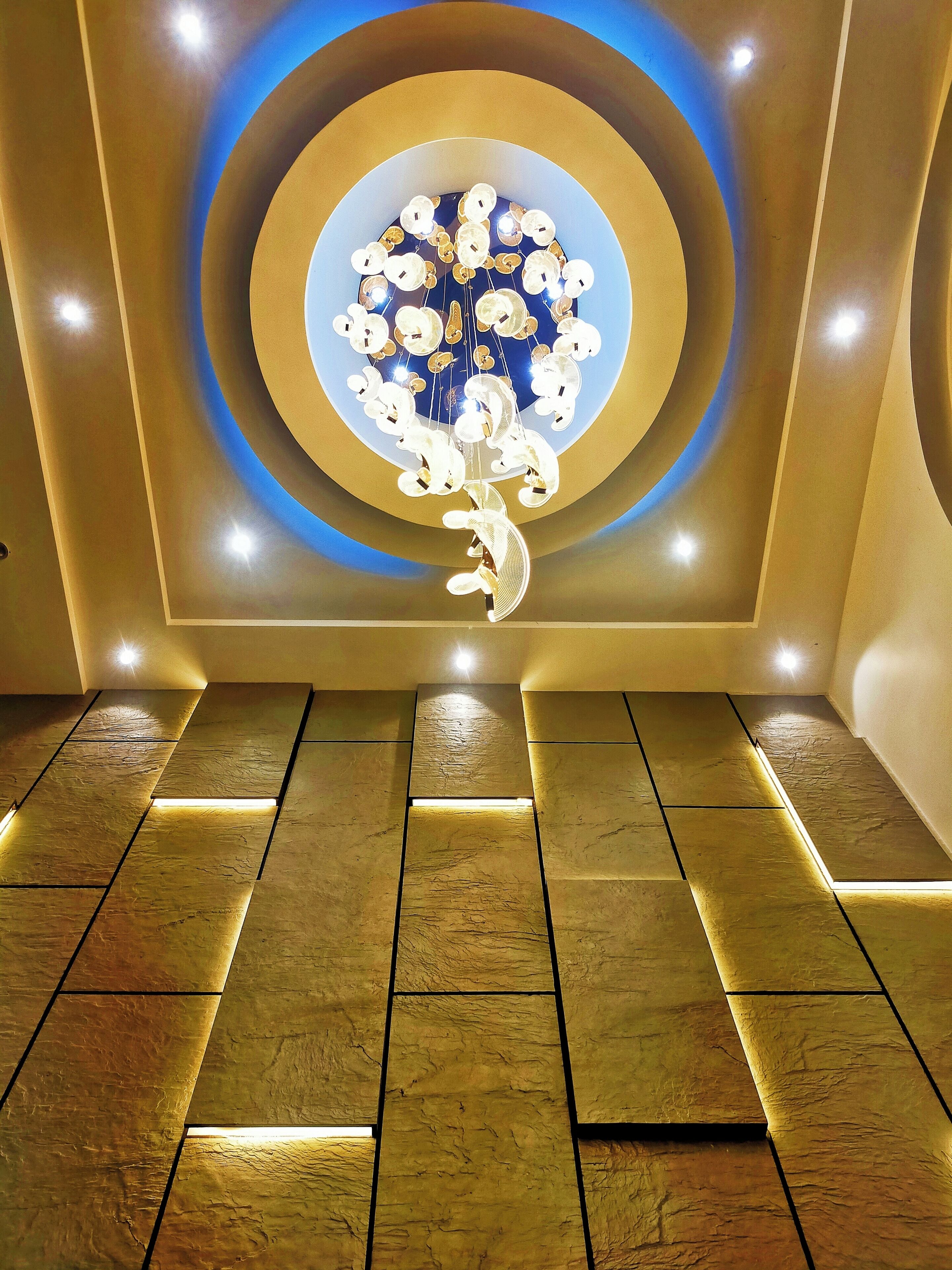 A modern interior with a circular light fixture and recessed ceiling lights.