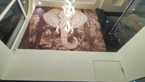 Un intérieur moderne agrémenté d’un lustre central, d’une lucarne circulaire et d’un sol à motifs.