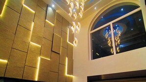 Un intérieur moderne avec un motif géométrique sur le mur, un luminaire suspendu et une grande fenêtre.