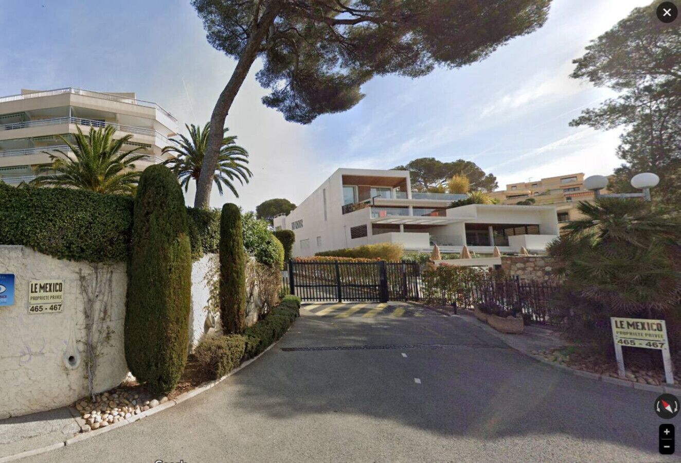 A gated residential area with a modern building, a private property sign, and a clear sky.