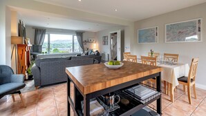 A modern kitchen with a wooden table, grey sofa, and dining area with wooden chairs. - 2 bedroom home in Kenmare with sea views to sleep 4 (Kenmare)