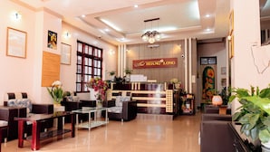Zona de recepción de un hotel, con mostrador, asientos y una barra de recepción.