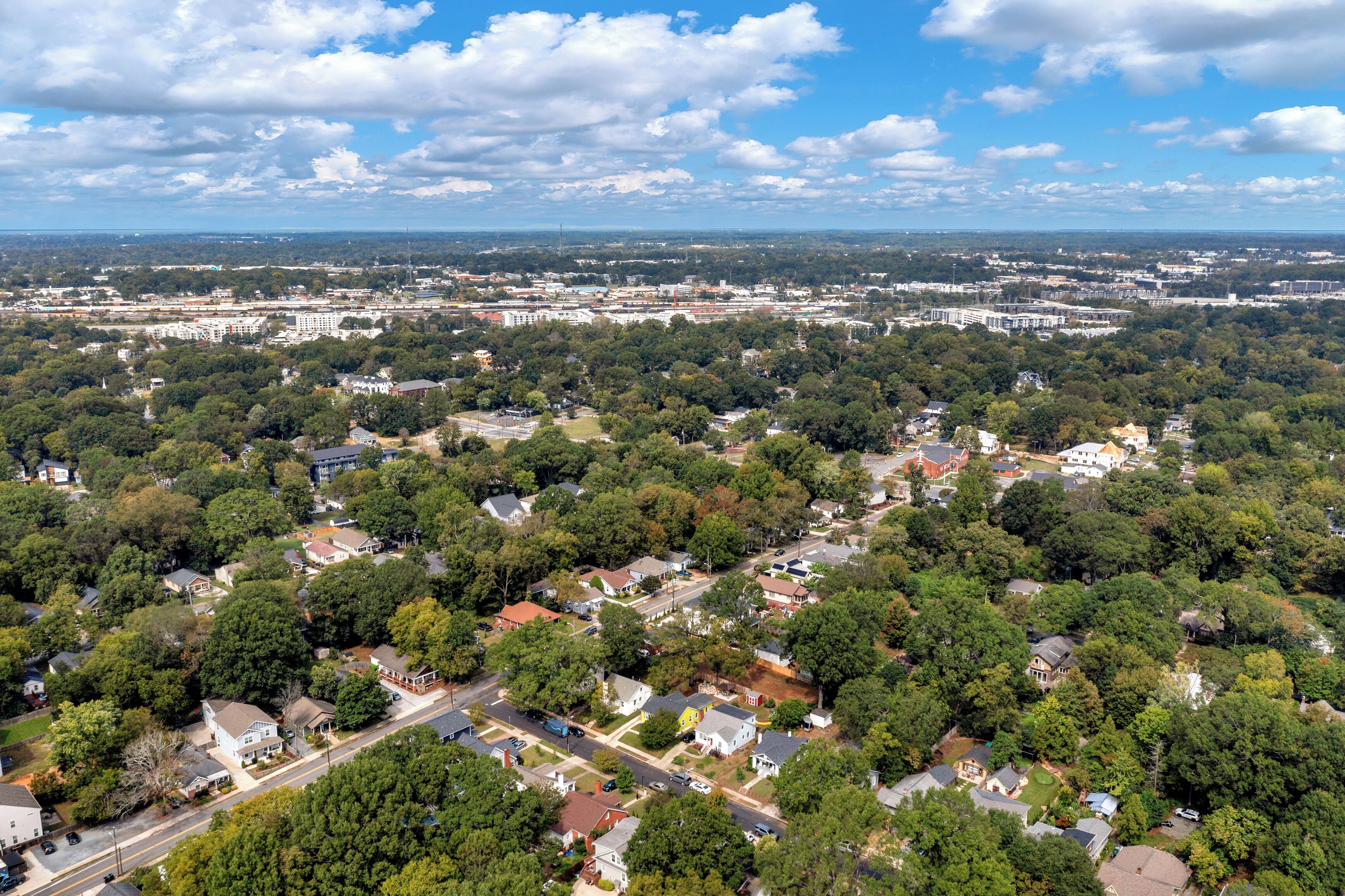 An aerial view of a residential area with houses, streets, and a distant cityscape.
