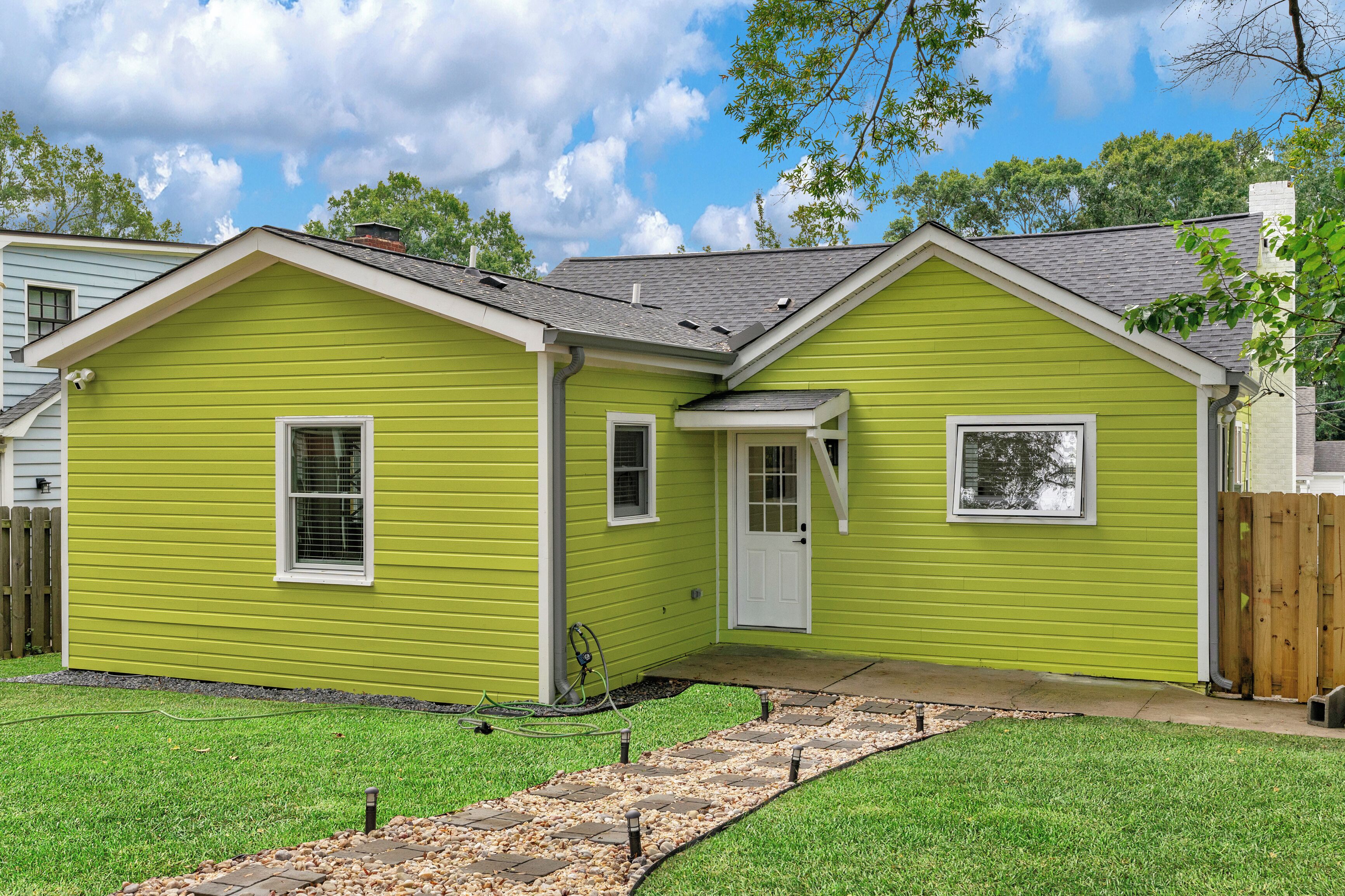 A two-story house with a green exterior, a front door, and a small attached garage.