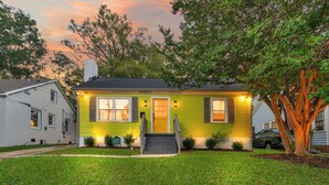 A two-story house with a front porch, a tree in the yard, and a driveway.