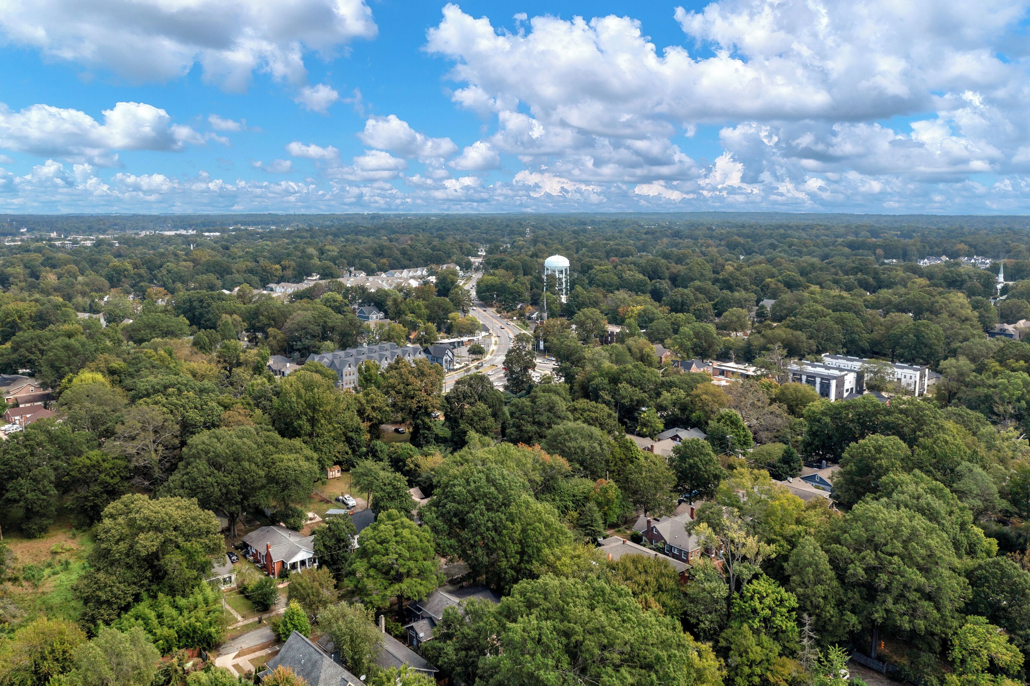 An aerial view of a residential area with houses, a water tower, and a church.