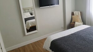 Hotellihuone, jossa on sänky, seinälle asennettu televisio ja peili, joka heijastaa sängyn.