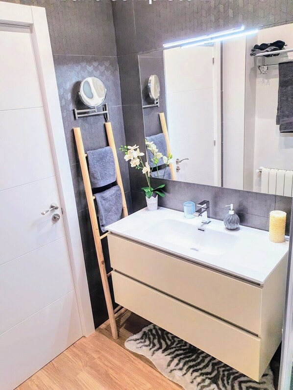 A modern bathroom with a white sink, mirror, and towel rack.