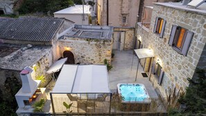 Un bâtiment en pierre doté d’un patio sur le toit, d’un jacuzzi et d’un espace salon extérieur.