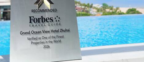 Une plaque d’hôtel ornée d’un ruban, symbole de la recommandation du guide Forbes Travel Guide.