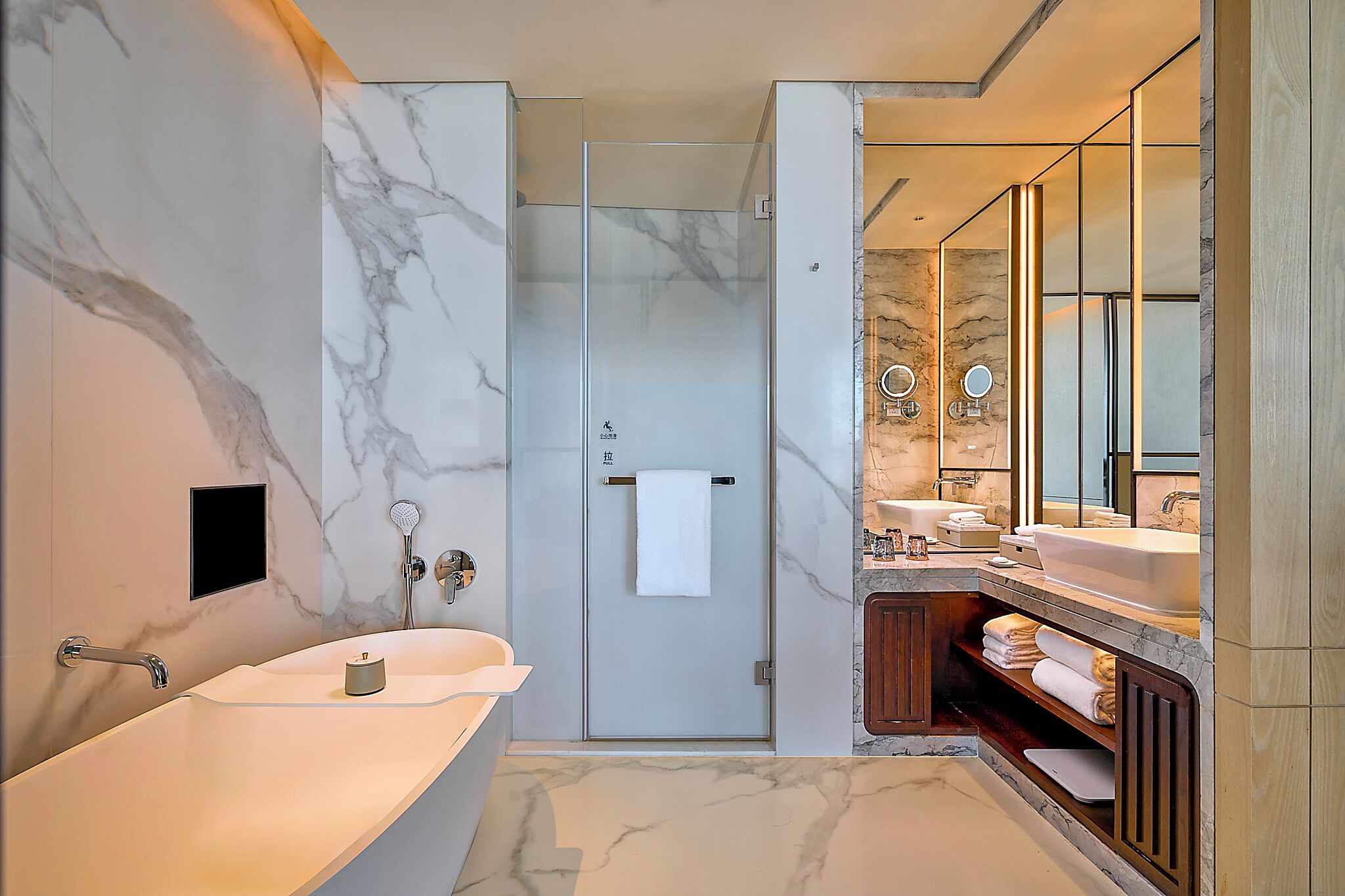 A modern bathroom with a dual sink, a glass shower enclosure, and a vanity with a mirror.