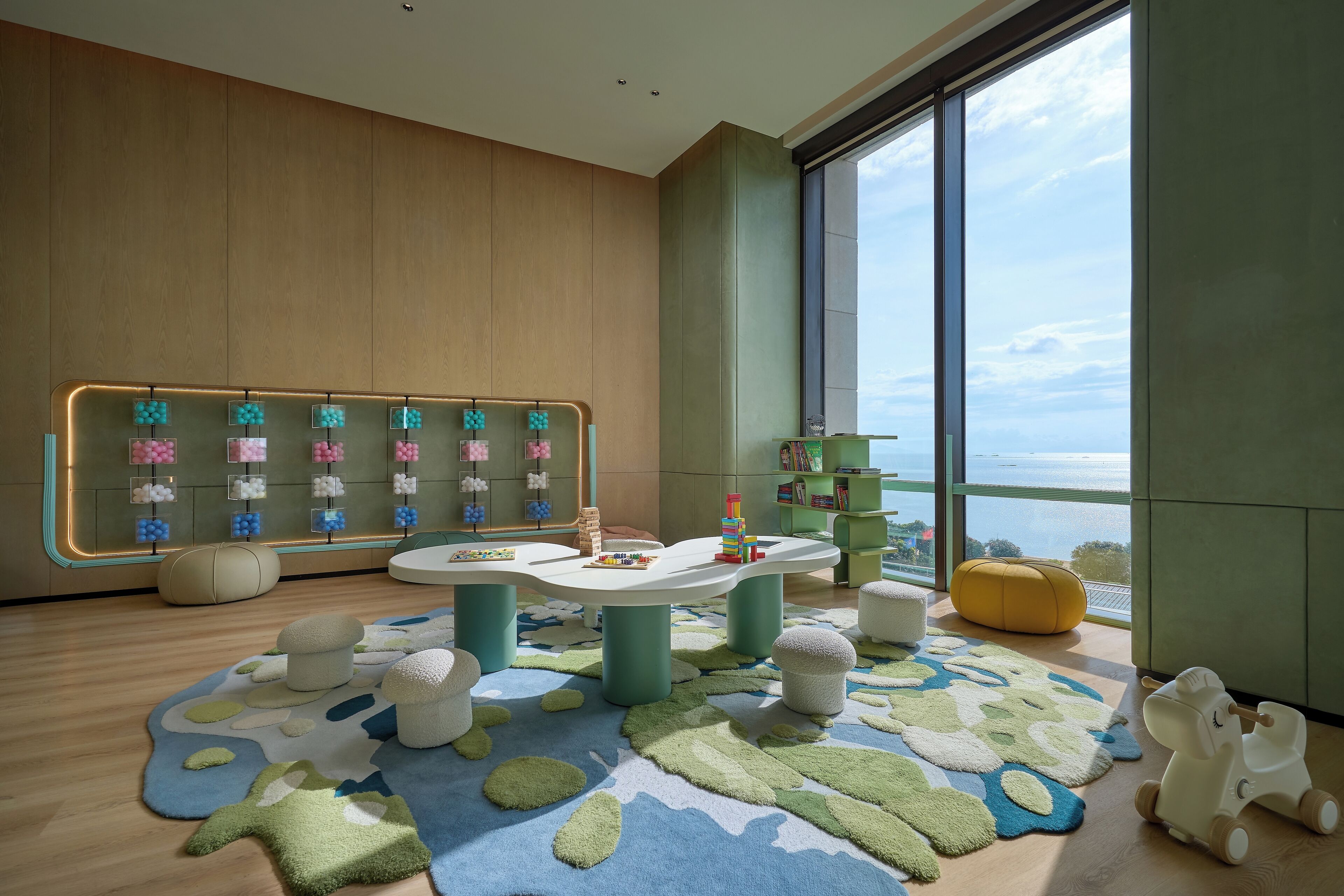 A modern children's play area with a large window, a play table, and a colorful rug.