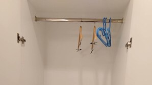 A small, enclosed room with a white interior, a metal rod with hooks, a radio, and a pair of scissors. - The Boone Hotel (Chiang Mai)